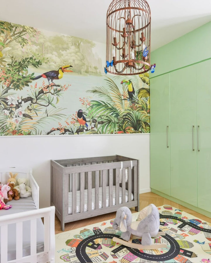 Real toucan jungle mural installed above a nursery crib in Dubai